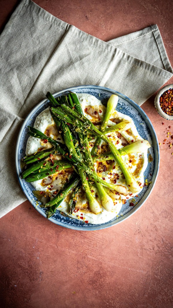 Charred Spring Onions with Whipped Feta & Burnt Butter | I’ve been loving this recipe using beautiful Irish spring onions from dunnesstores lately- they cook down so sweetly and bring a soft smokiness to the plate. The onions char beautifully, the feta gets whipped into creamy clouds, and the burnt butter ties the whole thing together with a nutty punch. adTime: 15 minutes
Serves: 2, as a side

1 bunch spring onions, roots trimmed
Olive oil
100g Dunnes Stores feta cheese
3 tbsp Dunnes Stores Greek style natural yogurt
Zest of a lemon
40g butter
½ tsp Dunnes Stores chili flakes 

Drizzle the spring onions with olive oil and place them in a hot cast iron pan or directly over a barbecue grill. Cook until the outsides are blistered and slightly blackened, and the insides are tender- turning occasionally to ensure even charring. This should take about 5–6 minutes total.
While the onions cook, add the feta, Greek yogurt, and zest of half a lemon to a food processor. Blitz until the mixture becomes smooth, light, and airy- it should have a creamy, spreadable texture. Taste and adjust with a pinch of salt if needed.
In a small saucepan, melt the butter over medium heat. Let it bubble and foam, swirling occasionally, until it turns a deep golden colour and smells rich and nutty- this takes just a few minutes. Keep a close eye on it, as it can burn quickly once it starts browning.
Spoon the whipped feta onto a serving plate, creating swoops with the back of a spoon. Arrange the charred spring onions on top. Drizzle generously with the burnt butter, letting it pool around the feta. Finish with a pinch of chili flakes for heat, and serve immediately.